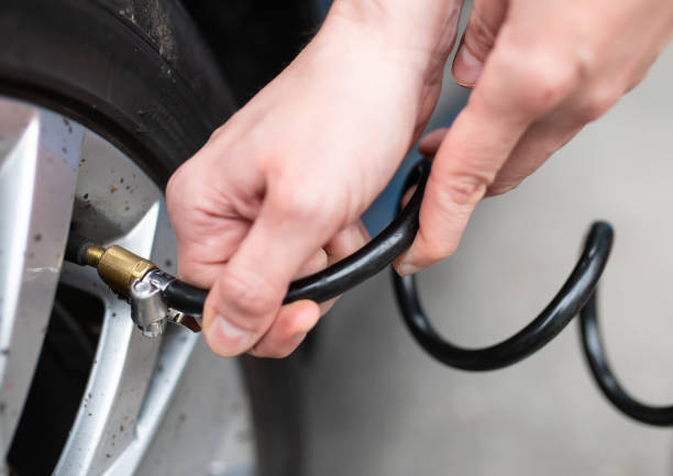 checks the air pressure on a car tire at a gas station.